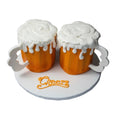 Two beer mug-shaped cakes with white "foam" frosting on a round stand with 'Cheers' text.