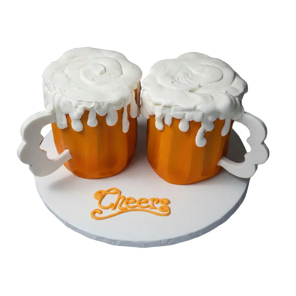 Two beer mug-shaped cakes with white "foam" frosting on a round stand with 'Cheers' text.