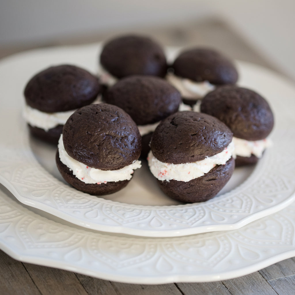Chocolate whoopie pies with cream filling on a decorative white plate.