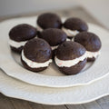 Chocolate whoopie pies with cream filling on a decorative white plate.