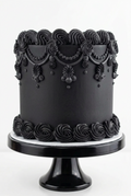 Elegant black Gothic cake with intricate Victorian-style buttercream piping, beaded swags, ornate decorative flourishes, and sculpted rosette borders on a black cake stand by The Makery Cake Co in Centennial, Colorado.