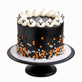 black cake with pumpkin, ghost, and bat sprinkles topped with white ghost buttercream poofs on a white board and black stand by The Makery Cake Co in Denver