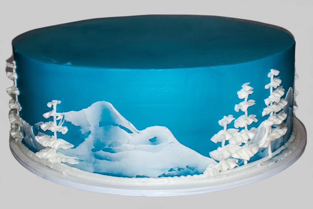 Blue cake with snowy mountain and tree design on a gray background