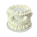 White frosted cake with decorative patterns on a white background