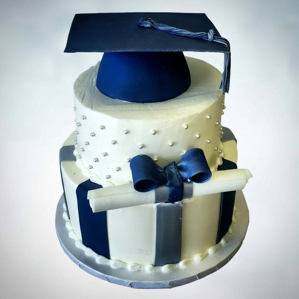 3 tier Graduation Cake, bottom tier with fondant vertical stripes, middle tier with dots and a graduation scroll wrapped in a bow, and the top tier an edible graduation hat