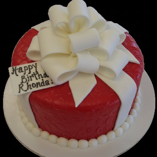 A red iced cake with a white multi loop bow on top